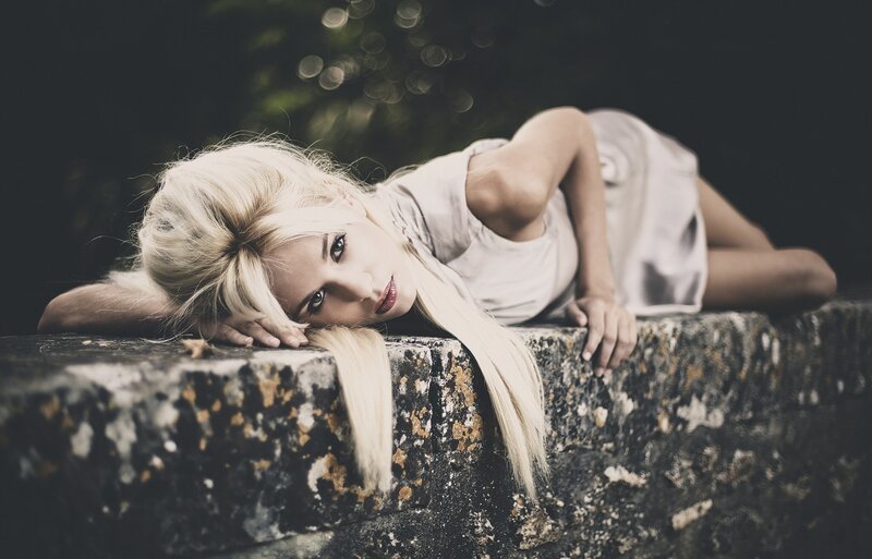 woman with blonde hair lying on stone