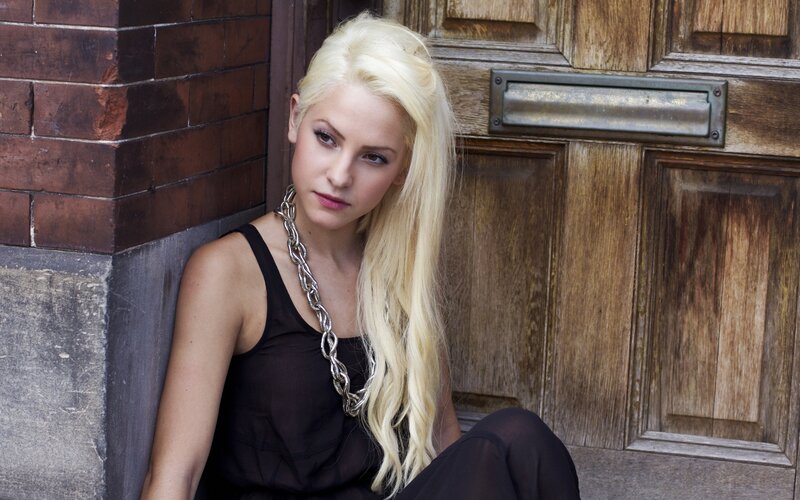 woman with blonde hair sitting by door