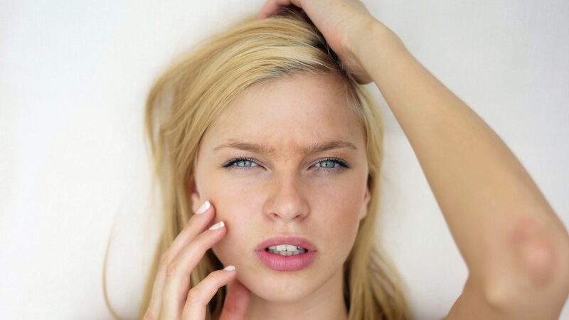 woman with blonde hair touching face