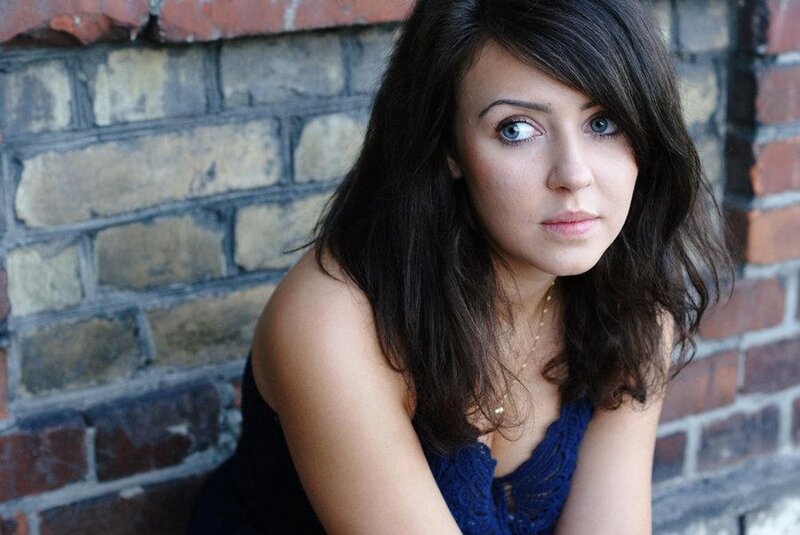 woman with blue eyes against brick wall