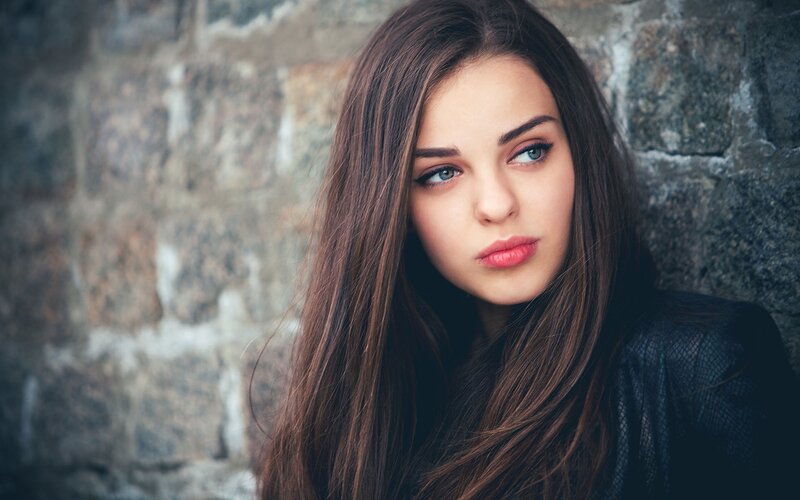 woman with blue eyes against stone wall