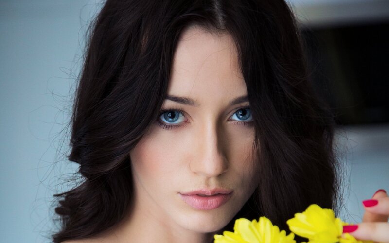 woman with blue eyes holding yellow flowers