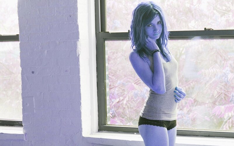 woman with blue skin standing by window