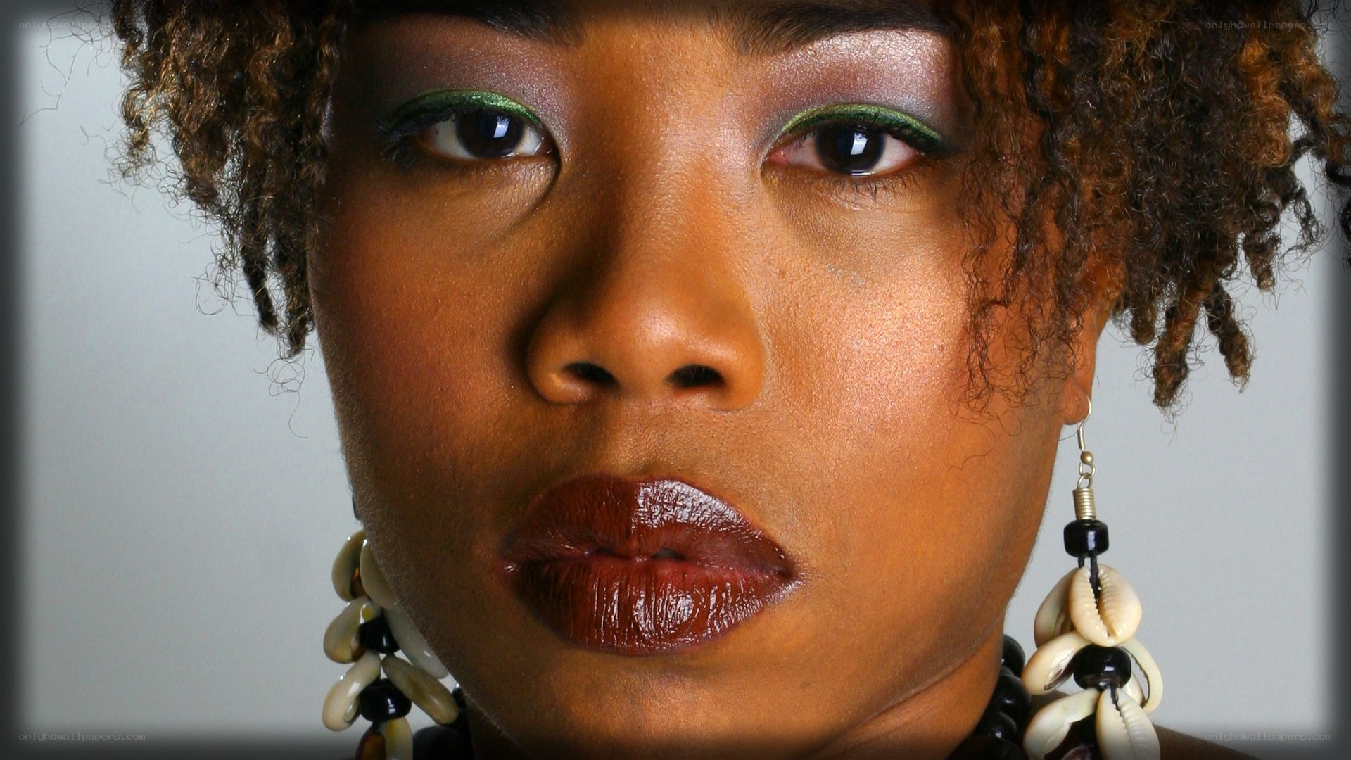 woman with bold makeup and shell earrings