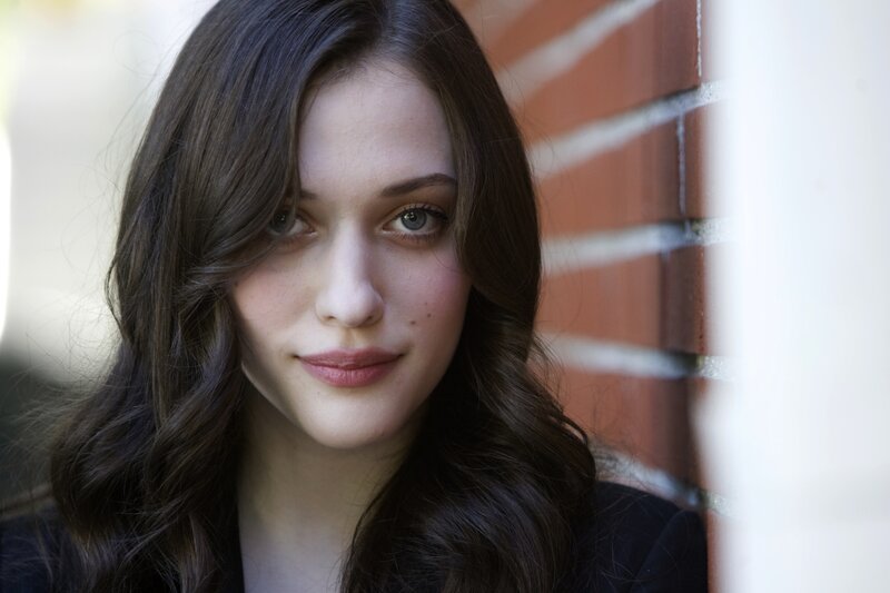 woman with brown hair against brick wall