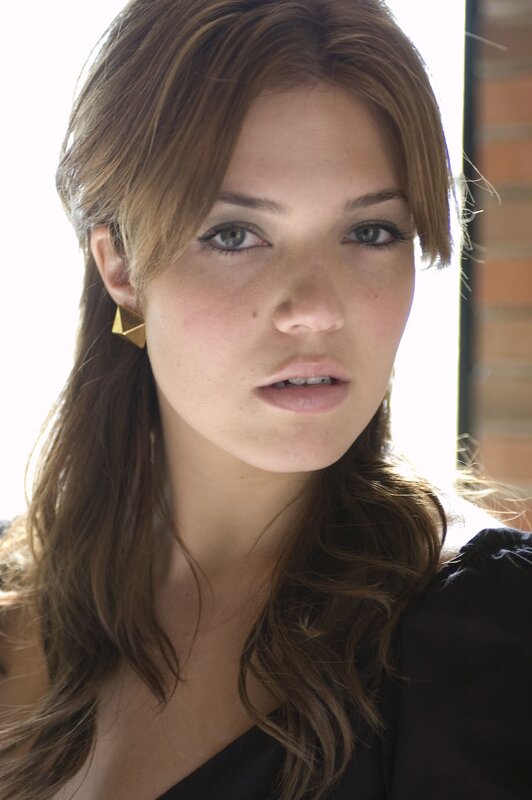 woman with brown hair and gold earrings