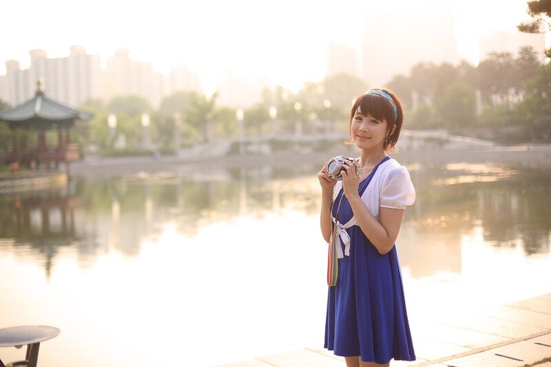 Woman with camera by a lake