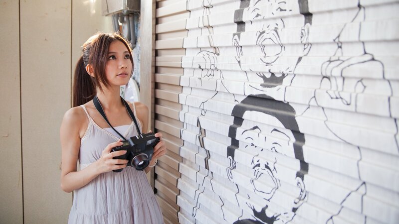 Woman with camera near graffiti wall