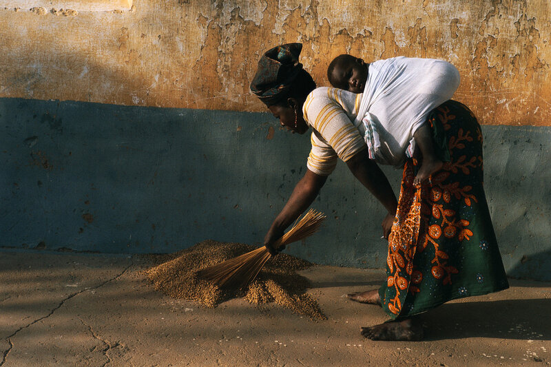Woman with child sweeping grain