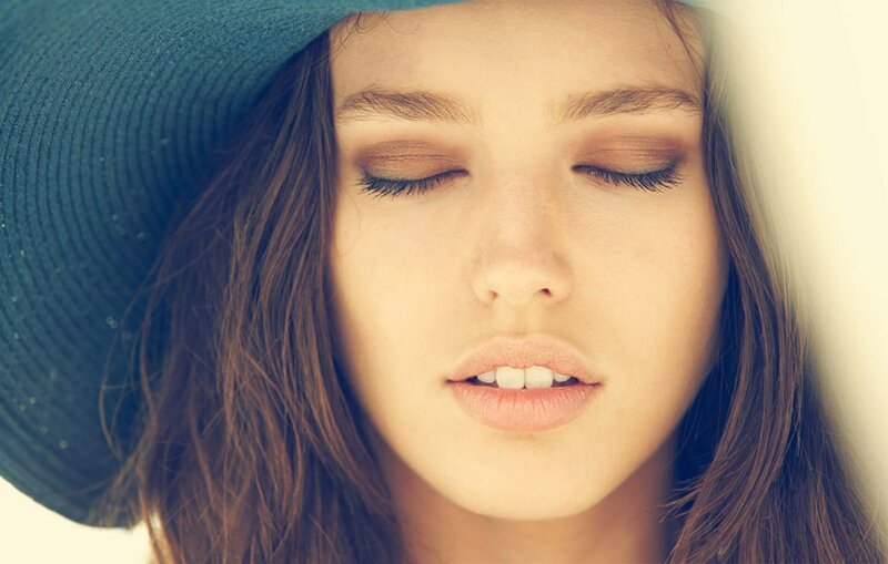 woman with closed eyes wearing hat
