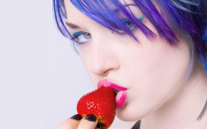 woman with colorful hair eating strawberry