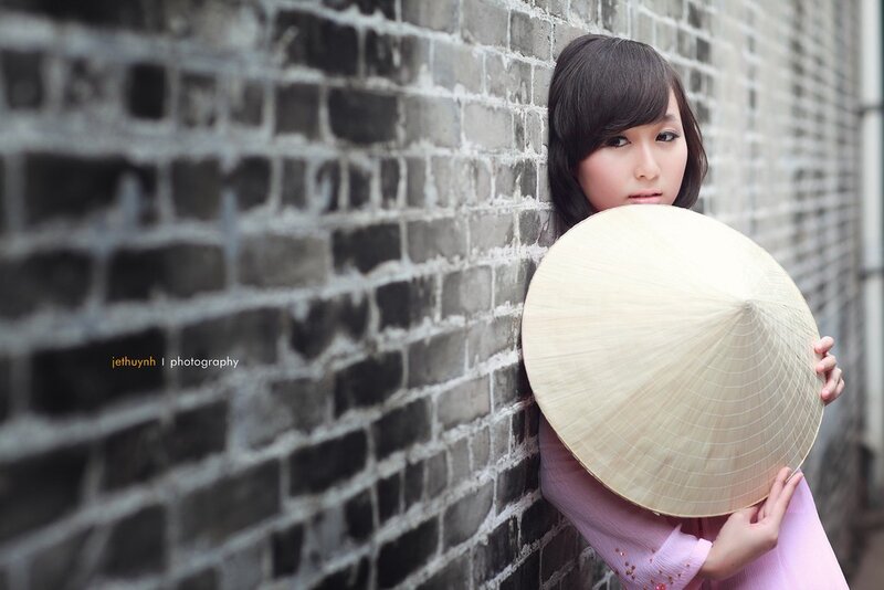 woman with conical hat against brick wall