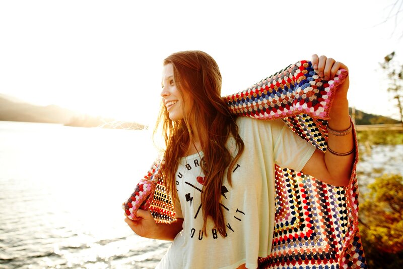 Woman with crocheted blanket by water