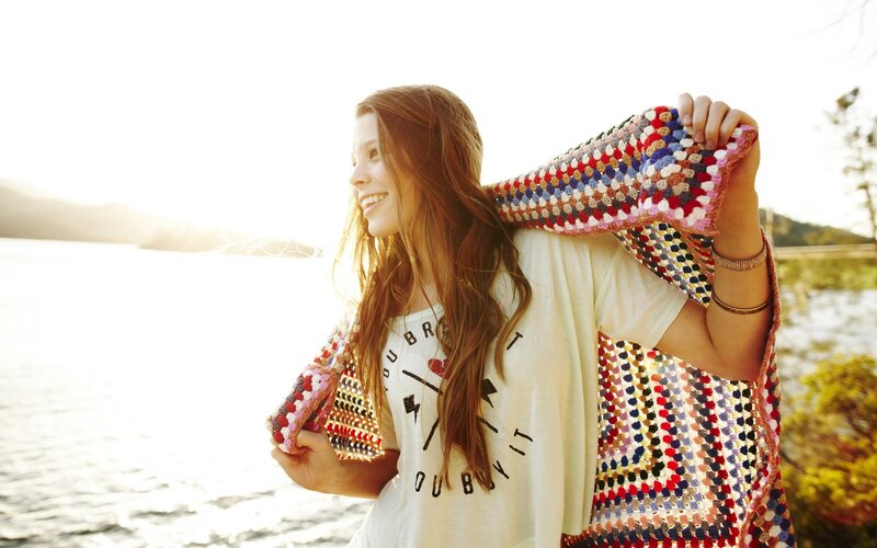 Woman with crocheted blanket by water