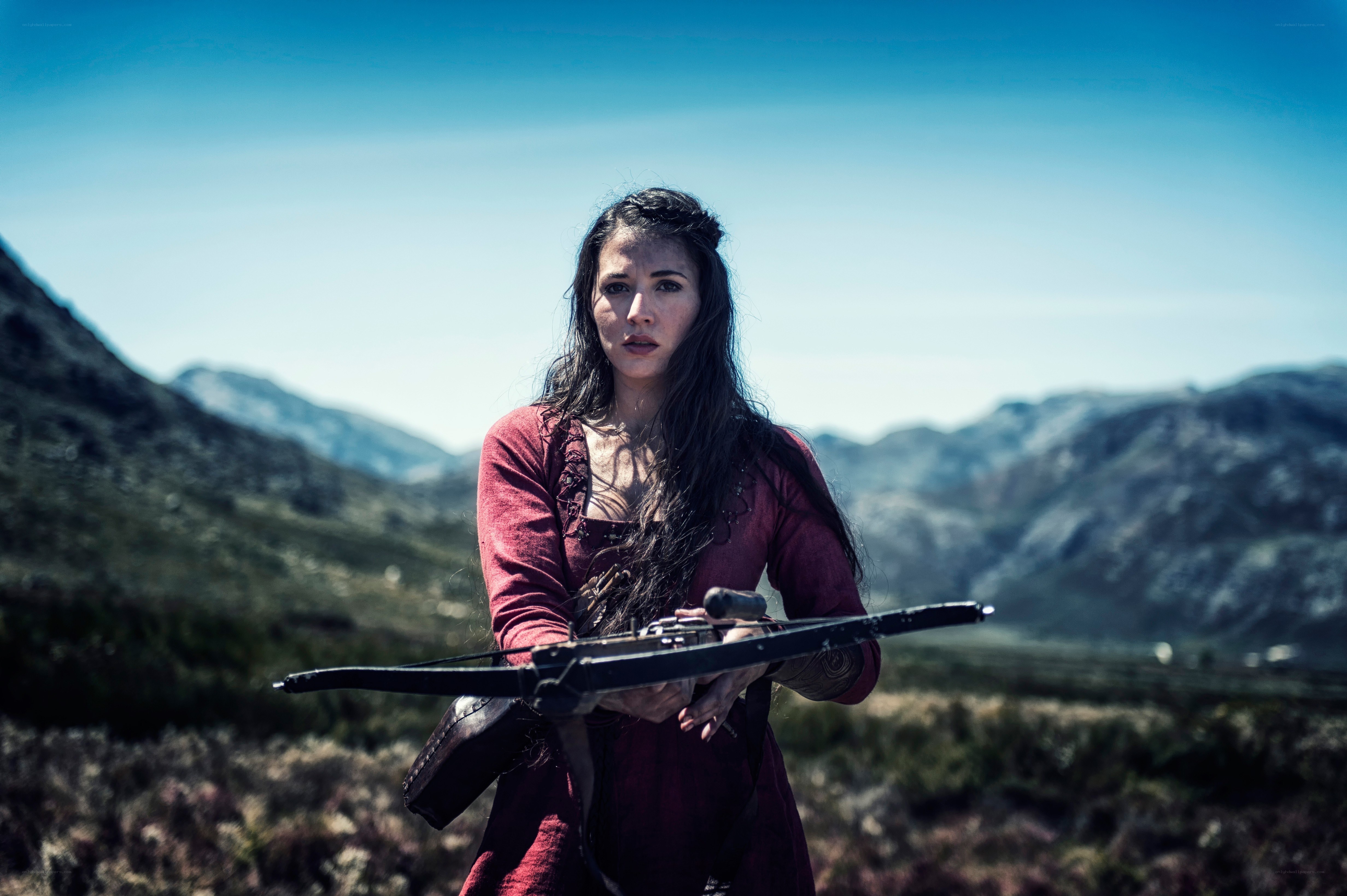 Woman with crossbow in mountains