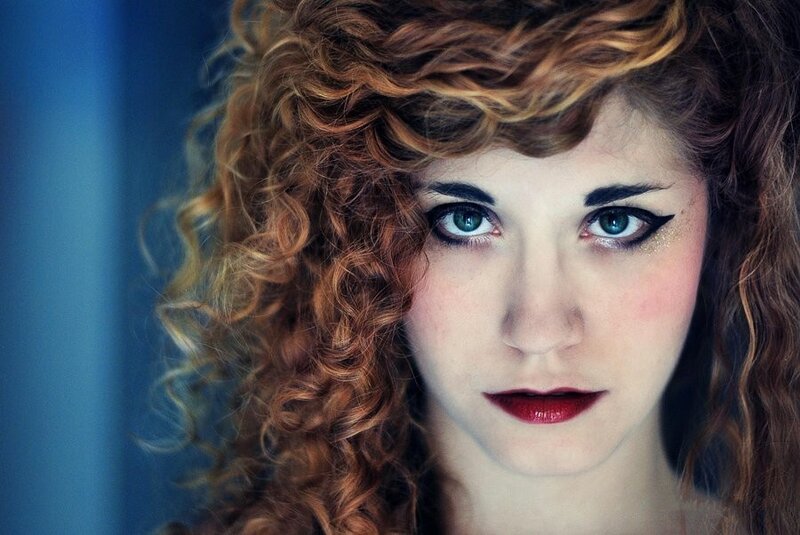 woman with curly hair and dramatic makeup