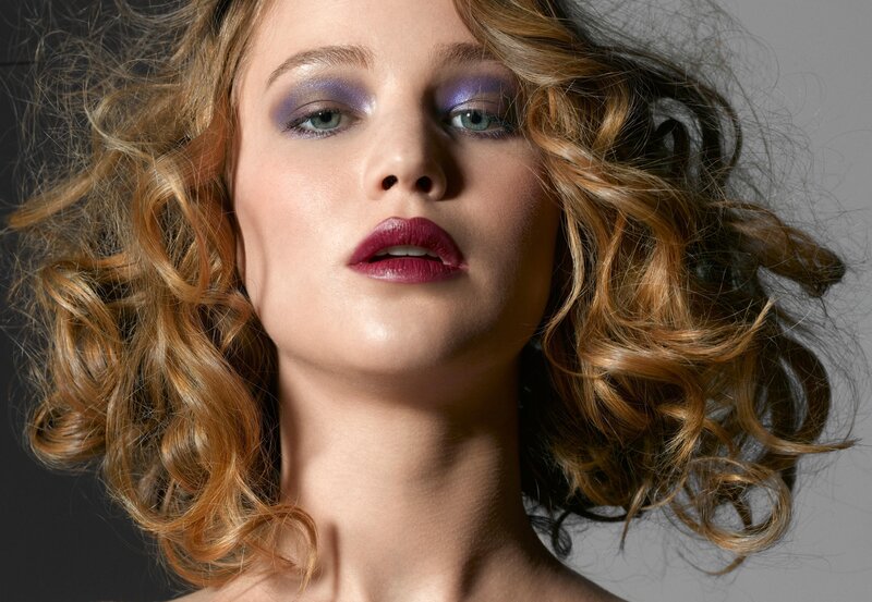 woman with curly hair and purple makeup