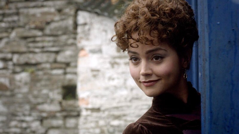 woman with curly hair by stone wall