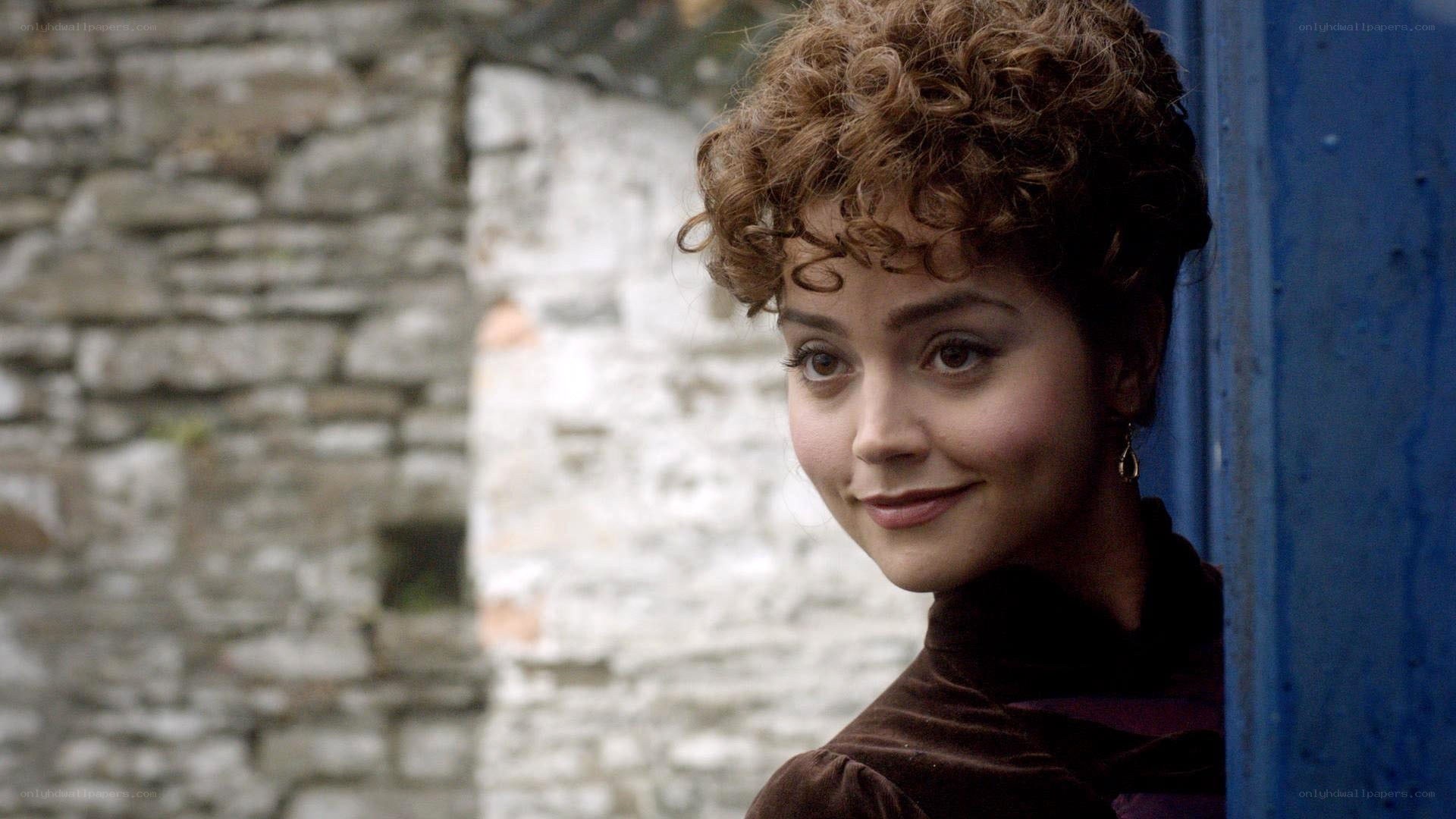 woman with curly hair by stone wall