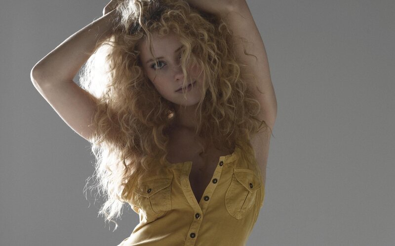woman with curly hair in yellow shirt