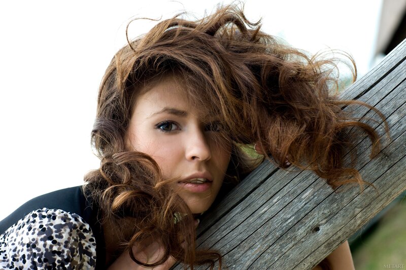 woman with curly hair leaning on wood