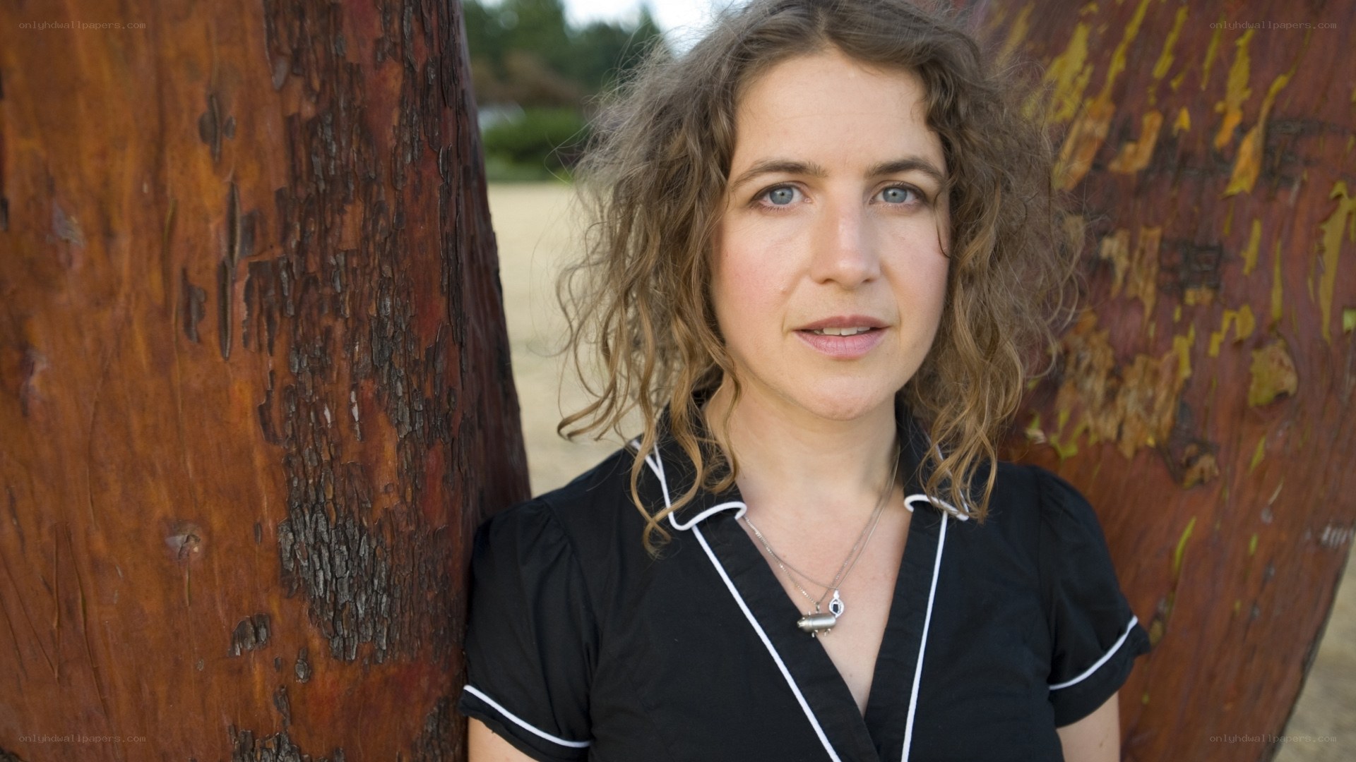 woman with curly hair standing by tree