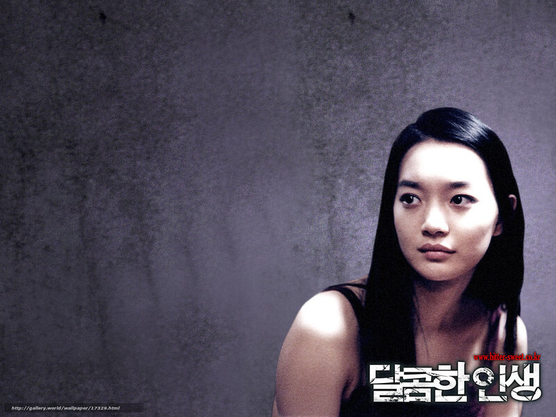 woman with dark hair against gray wall