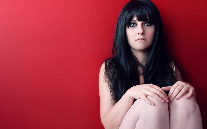 woman with dark hair against red wall