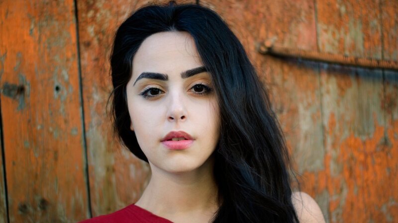 woman with dark hair against wooden wall