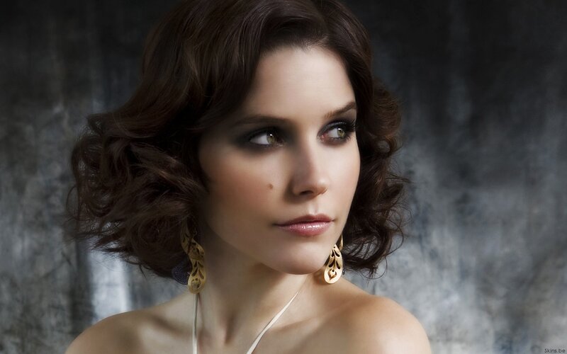 woman with dark hair and gold earrings