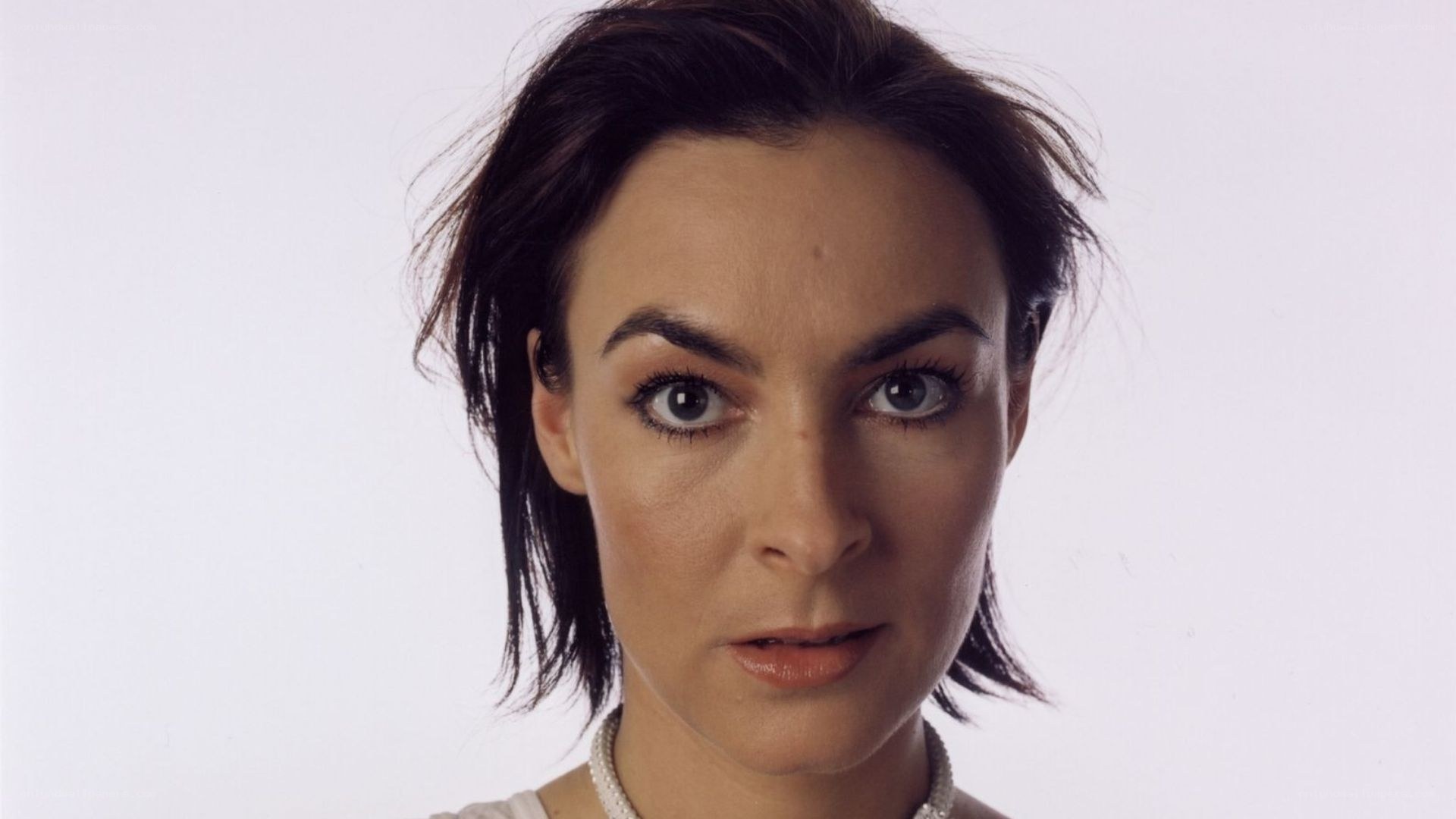 woman with dark hair and pearl necklace