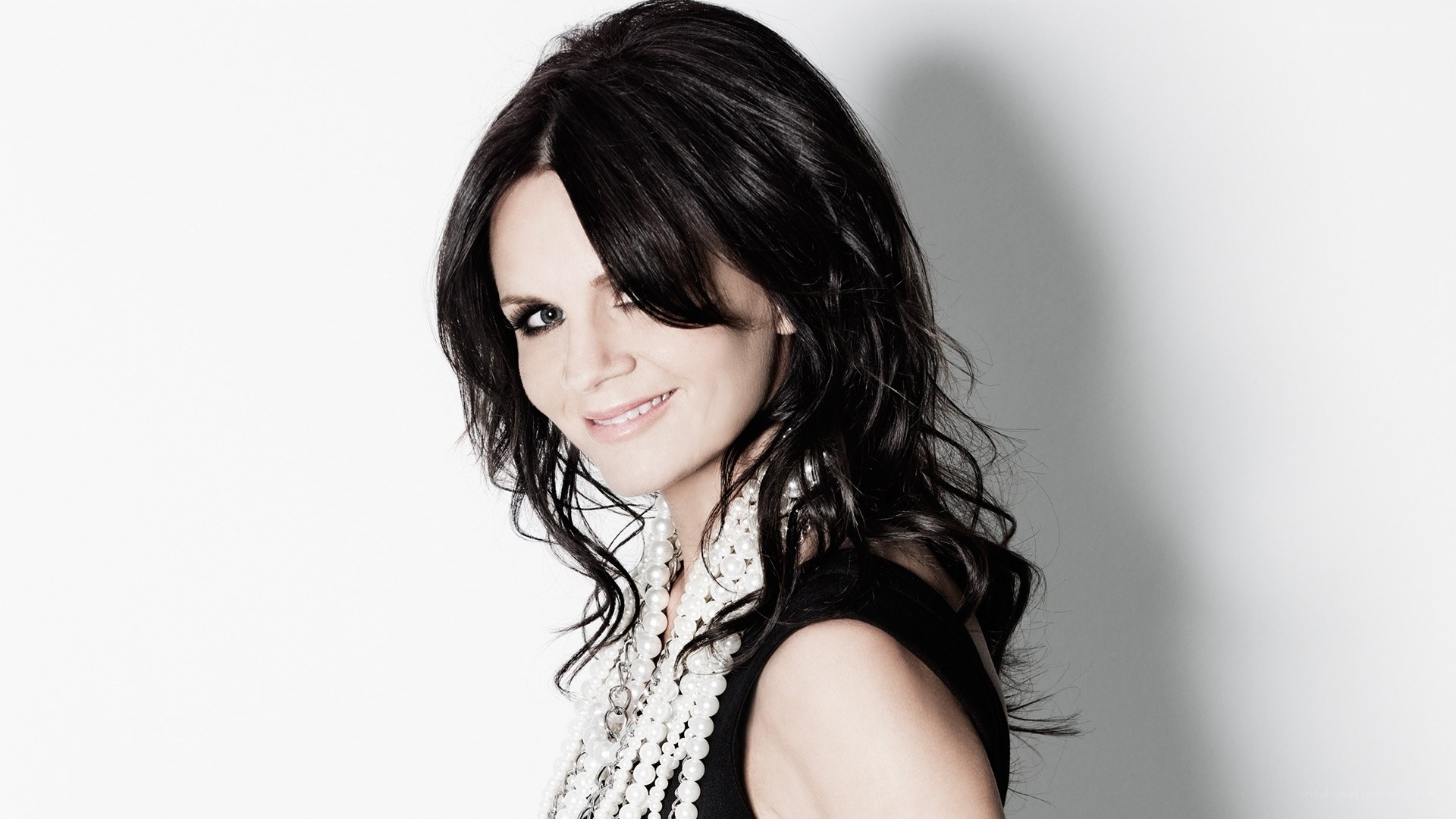 woman with dark hair and pearls