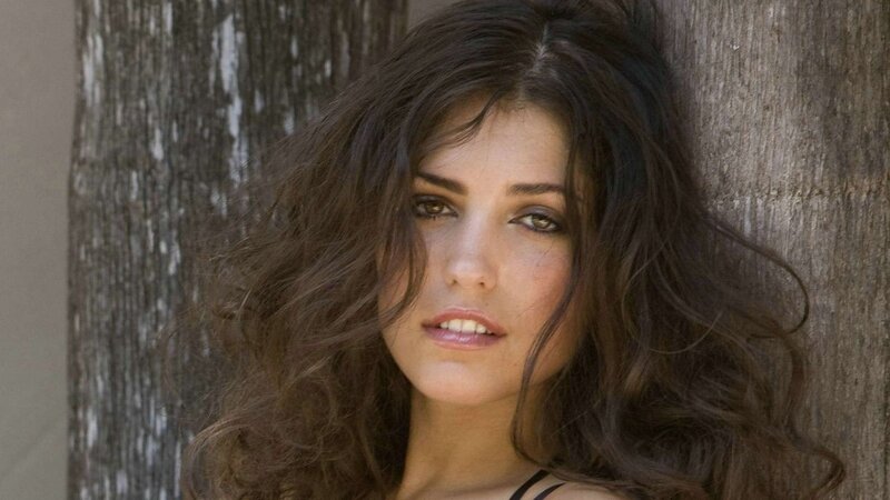 woman with dark hair leaning on tree