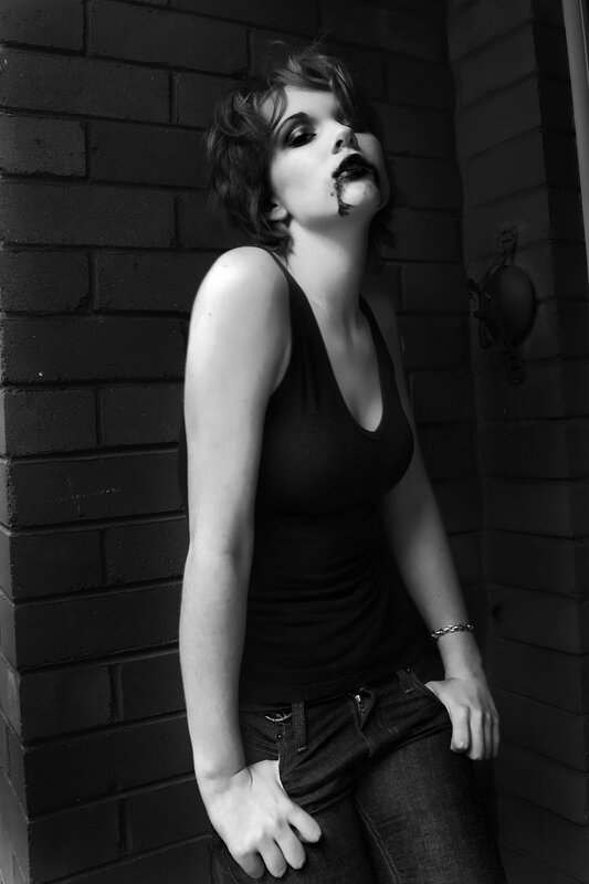 woman with dark makeup leaning against wall