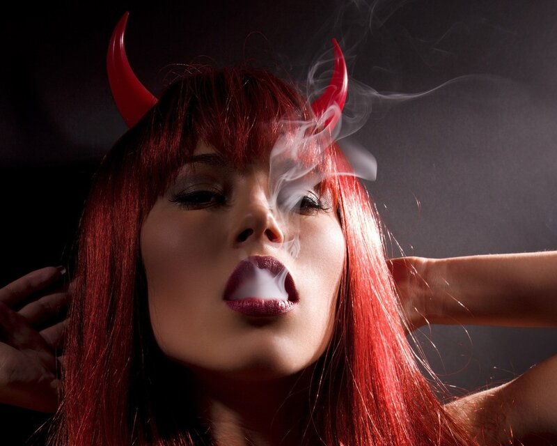woman with devil horns exhaling smoke