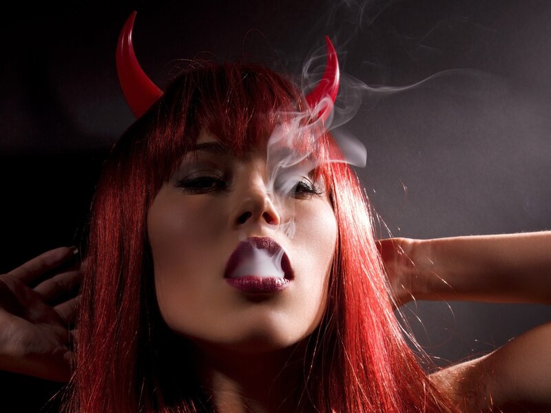 woman with devil horns exhaling smoke