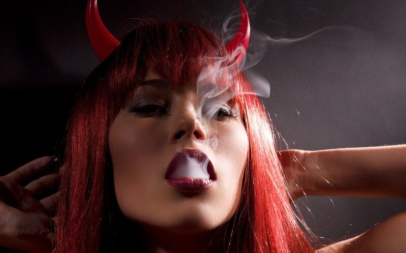 woman with devil horns exhaling smoke
