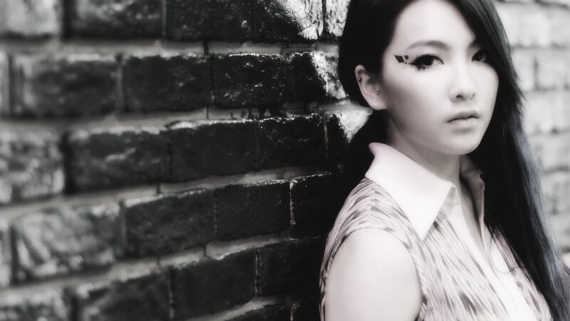 woman with dramatic makeup against brick wall