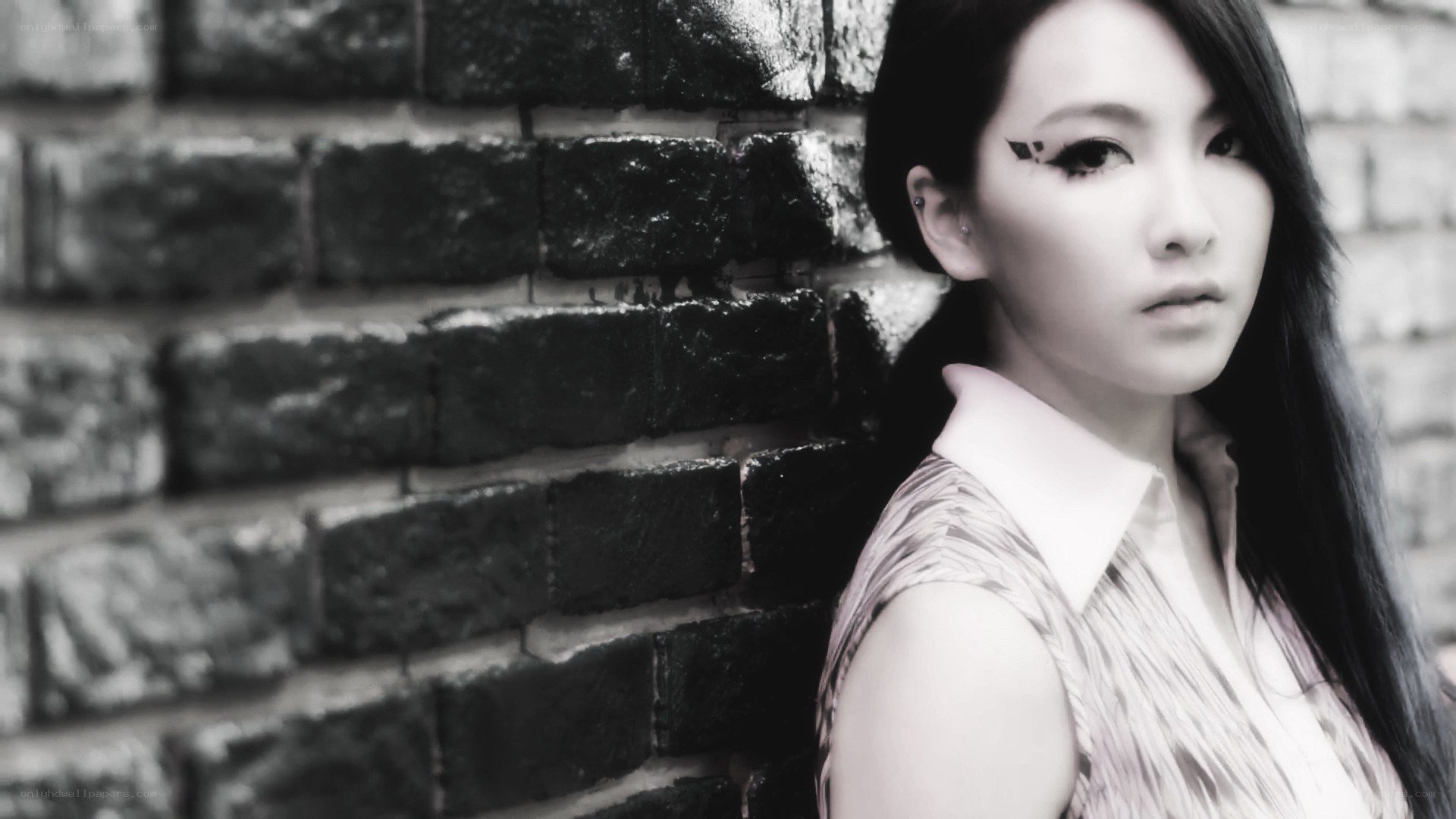 woman with dramatic makeup against brick wall