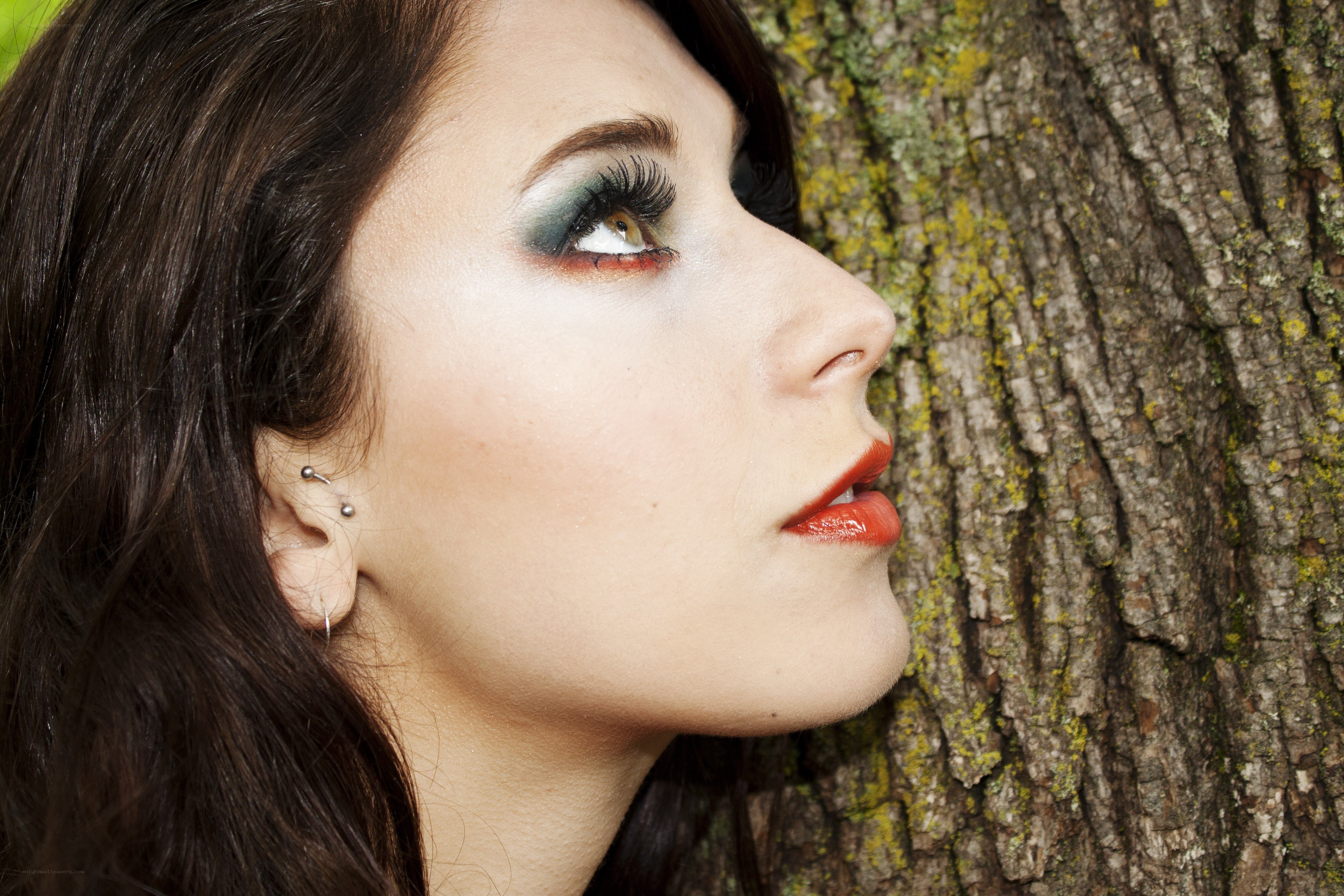 woman with dramatic makeup leaning on tree