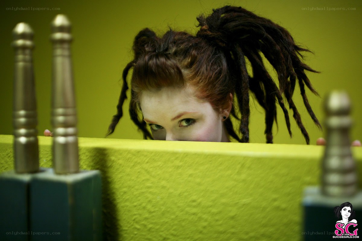 woman with dreadlocks peeking over wall