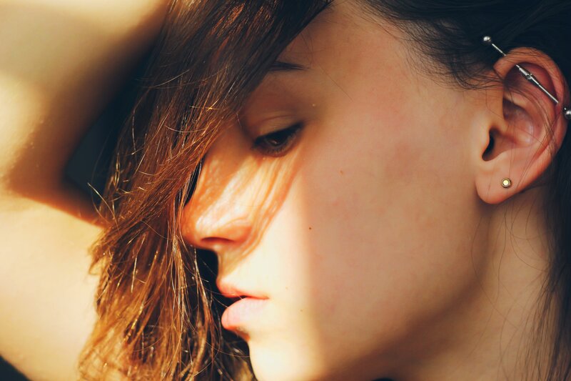 woman with ear piercings in sunlight
