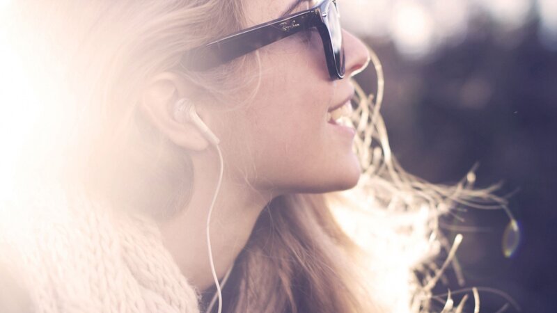woman with earbuds and sunglasses