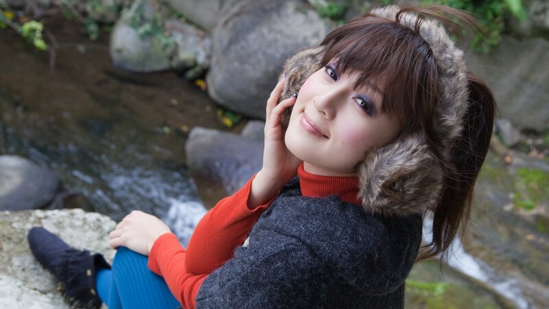 Woman with earmuffs by a stream