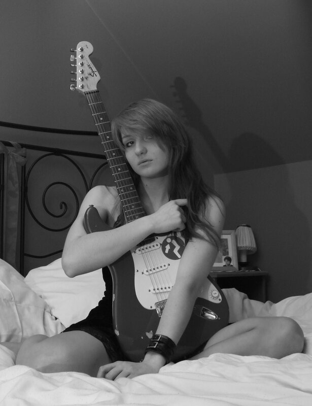 woman with electric guitar on bed
