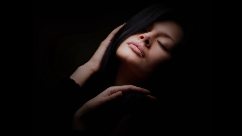 woman with eyes closed in darkness