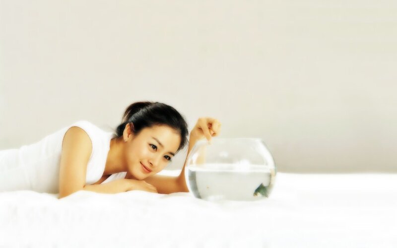 woman with fishbowl on bed
