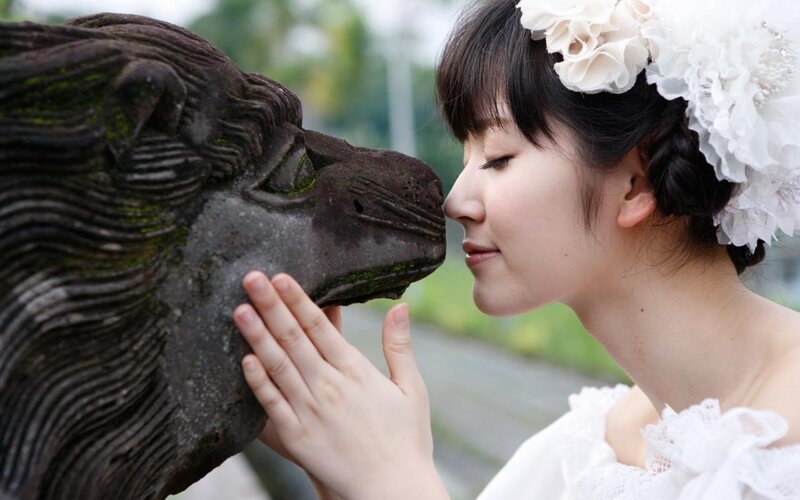 woman with floral crown touching statue