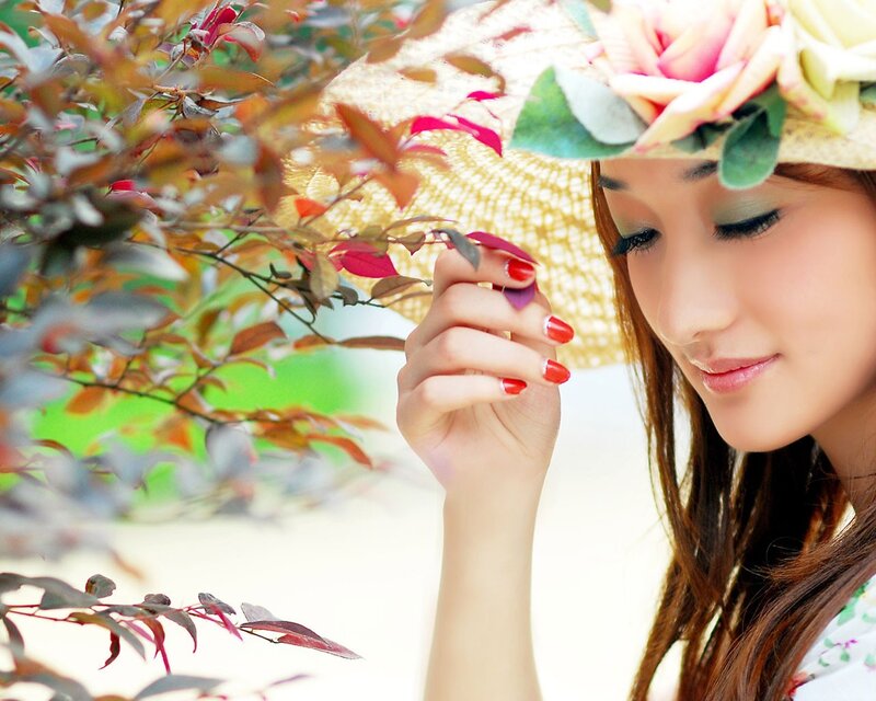 woman with flower hat smelling leaves