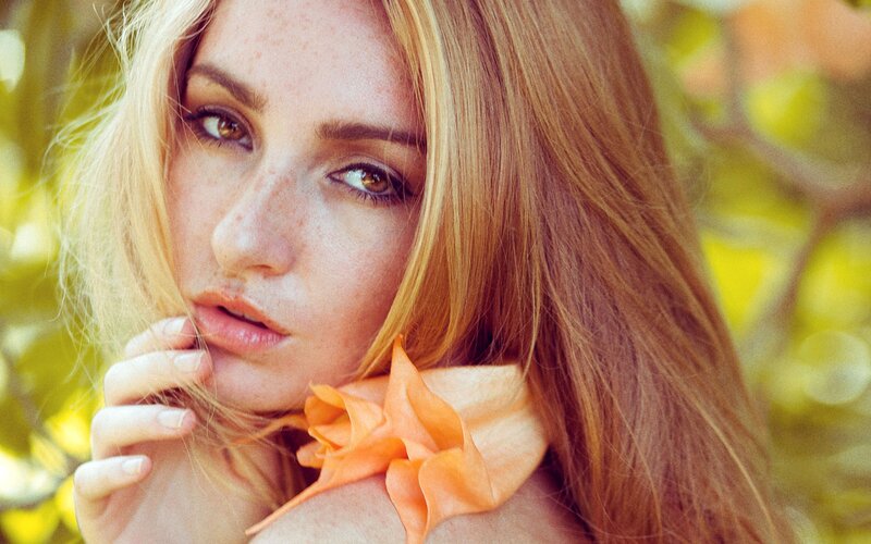 woman with freckles and orange flower